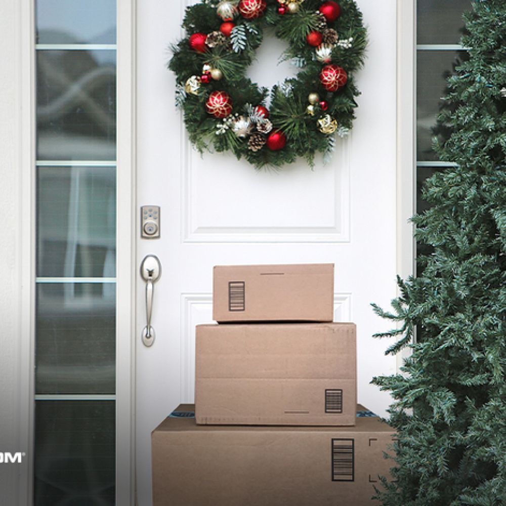 <span class="uk-h4">Packages stacked on front steps, behind it a white door with a smart lock and wreath. In the corner it reads ‘Power by Alarm.com’</span>