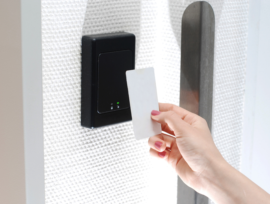 A hand uses a magnetic card to gain access to a door through a card reader.