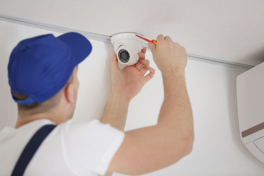 A technician adjusts a ceiling-mounted security camera.
