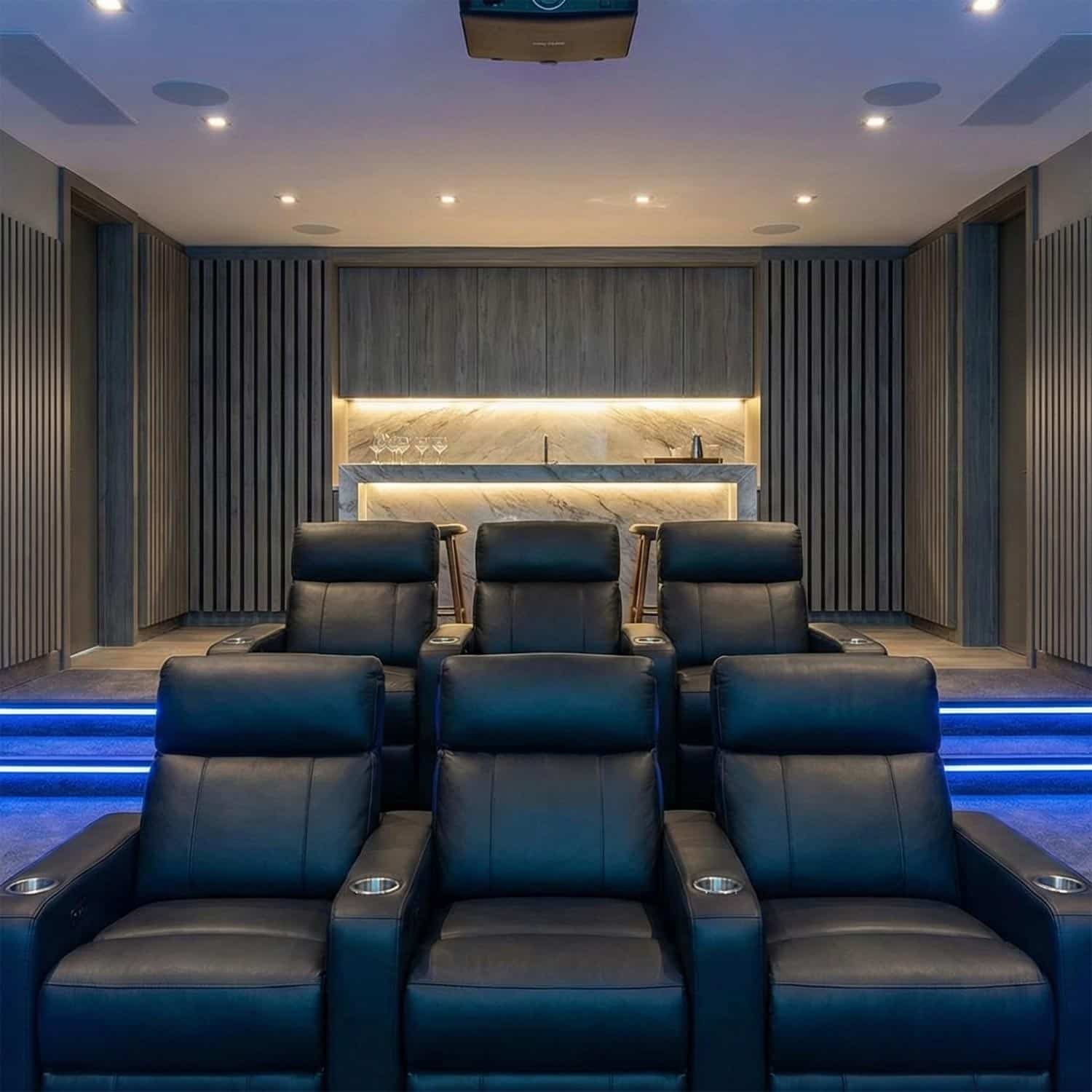 Modern home cinema with leather recliners and a marble bar counter