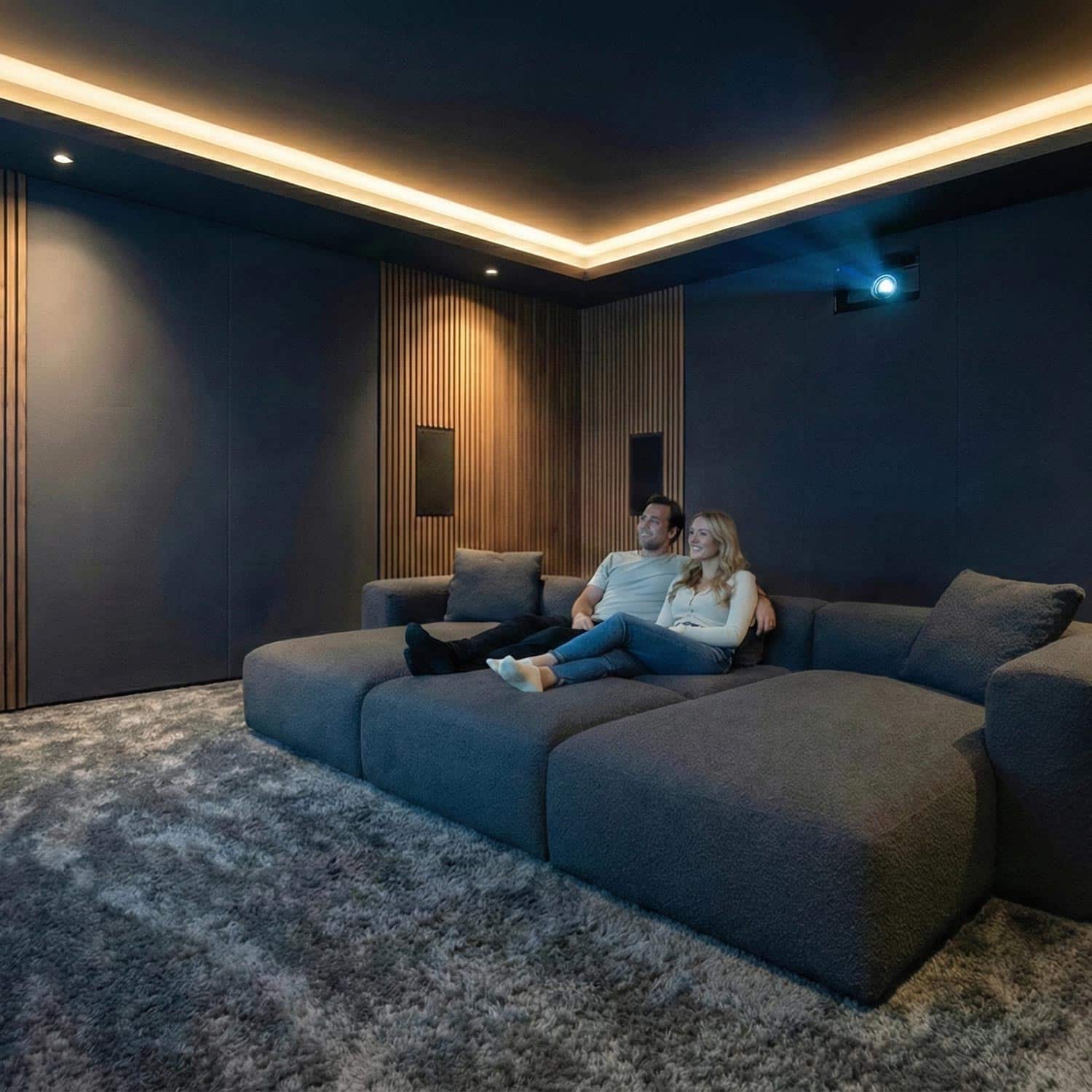 Couple relaxing on a large gray sectional in a dimly lit media room